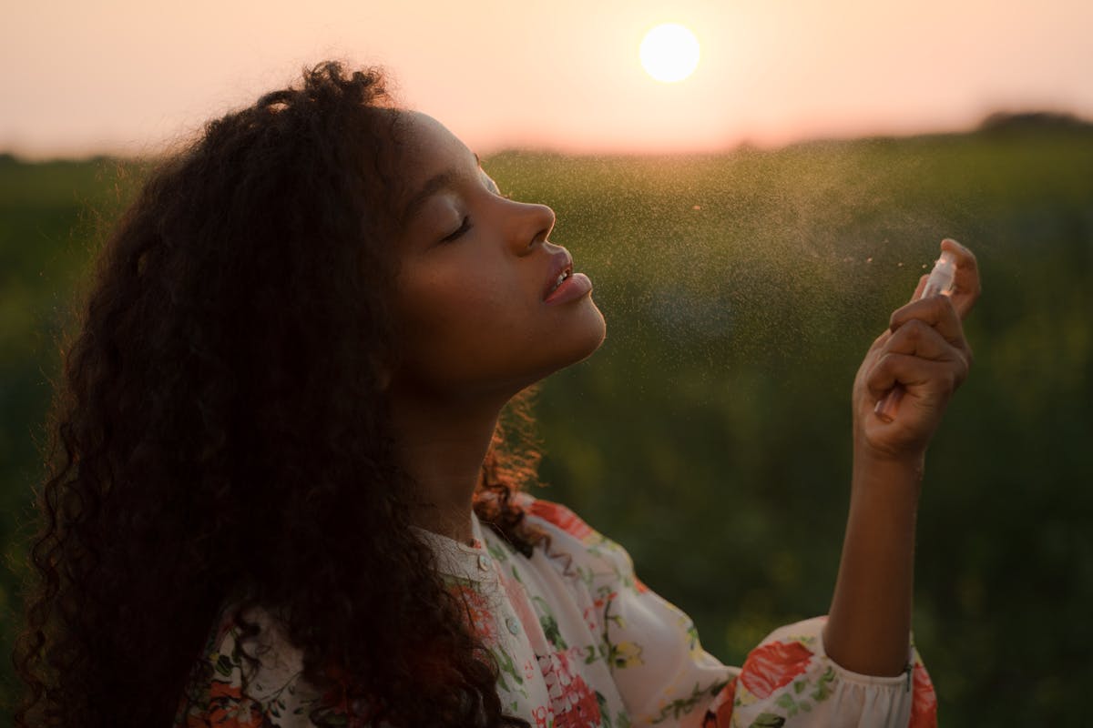 ragazza di colore spruzza profumo all'aria aperta