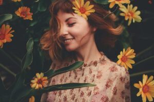 ragazza con capelli rossi e fiori che la attorniano