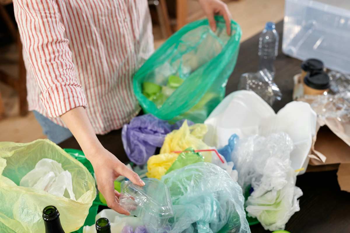 Una donna che mette ordine fra i sacchetti dei rifiuti in casa