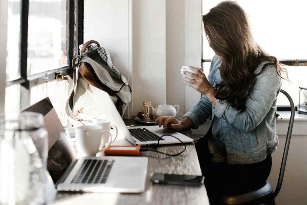 Una ragazza al computer che beve un caffè