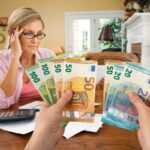 Una donna che consulta le bollette e soldi in euro tra due mani