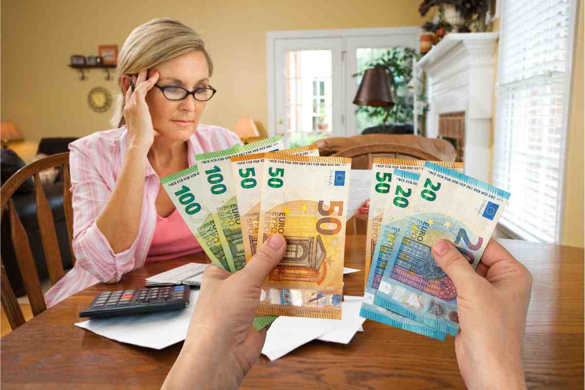 Una donna che consulta le bollette e soldi in euro tra due mani