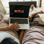 coppia sdraiata a letto guarda un film Netflix sul pc portatile