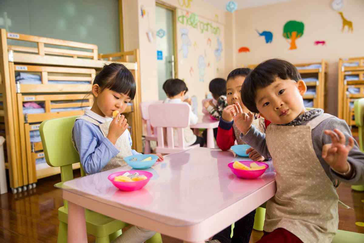 bimbi a tavolo che mangiano all'asilo