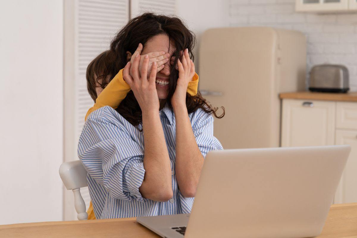 mamma al pc con bambino che le copre gli occhi