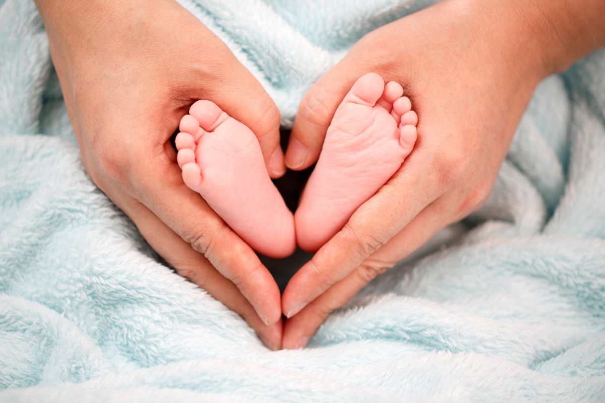 I piedini di un neonato nelle mani di una persona adulta
