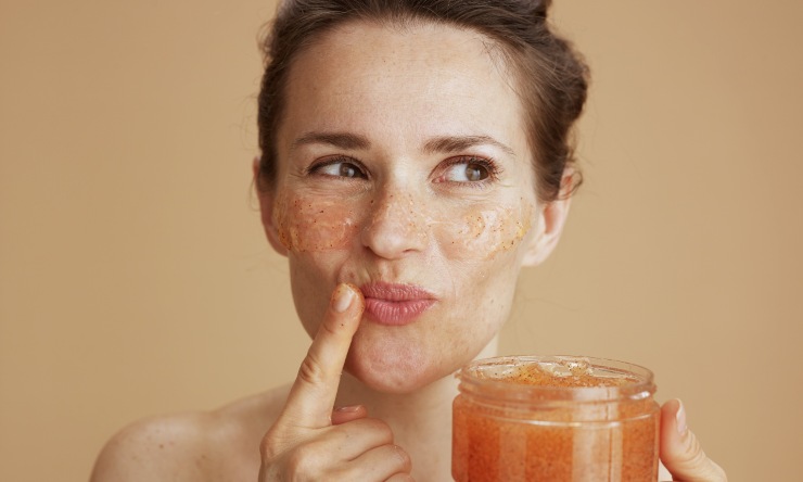 Donna che fa lo scrub viso