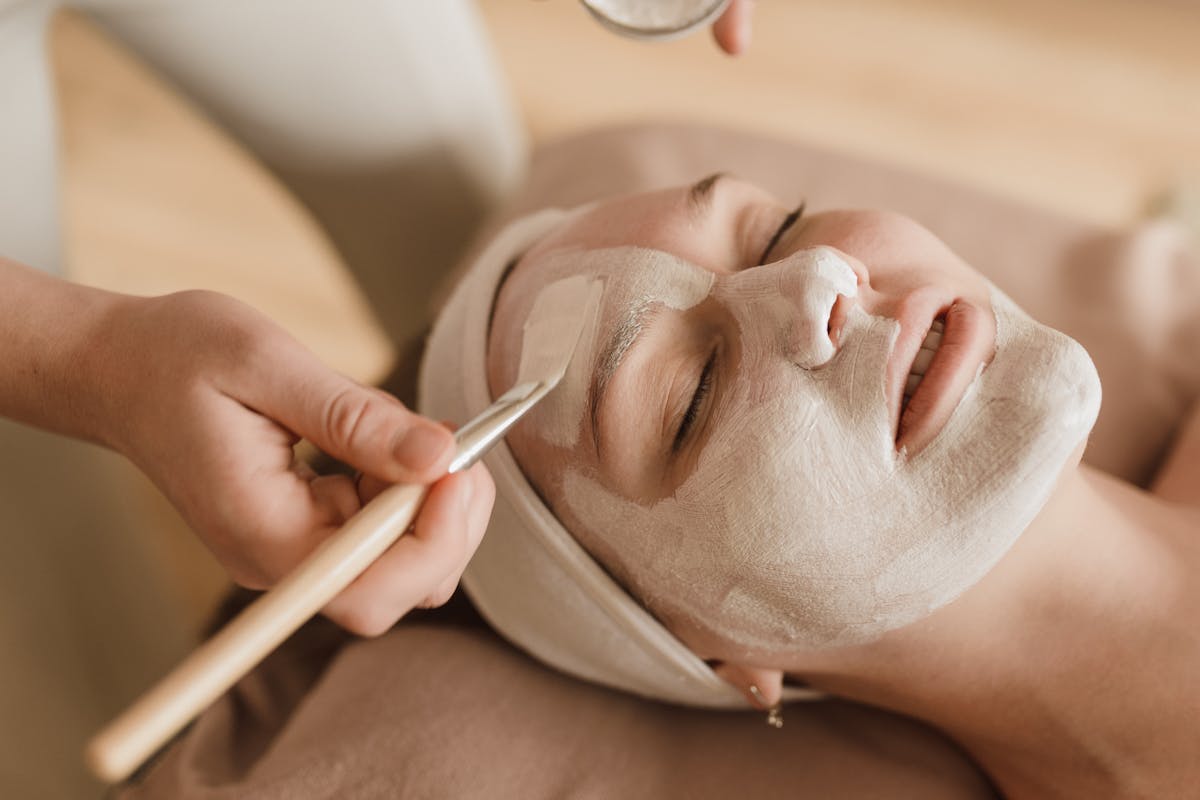 viso pieno di crema spalmata da operatrice con pennello