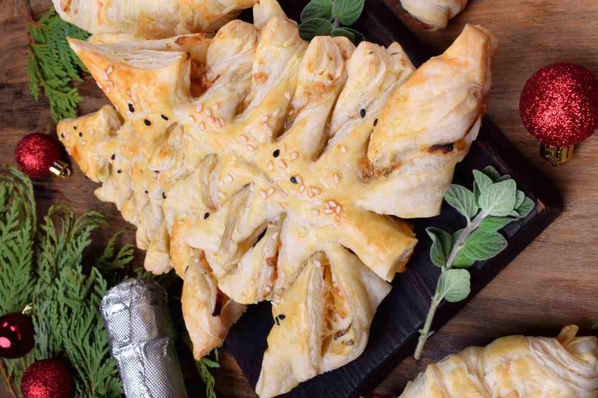 albero di natale di pasta sfoglia con prosciutto e formaggio su un vassoio