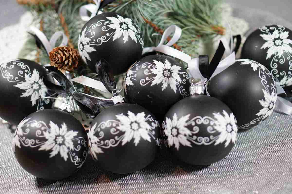 una serie di palline di Natale nere con piccole decorazioni bianche su un tavolo