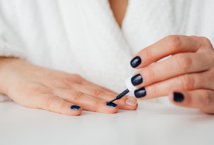 Donna che applica lo smalto alle unghie 