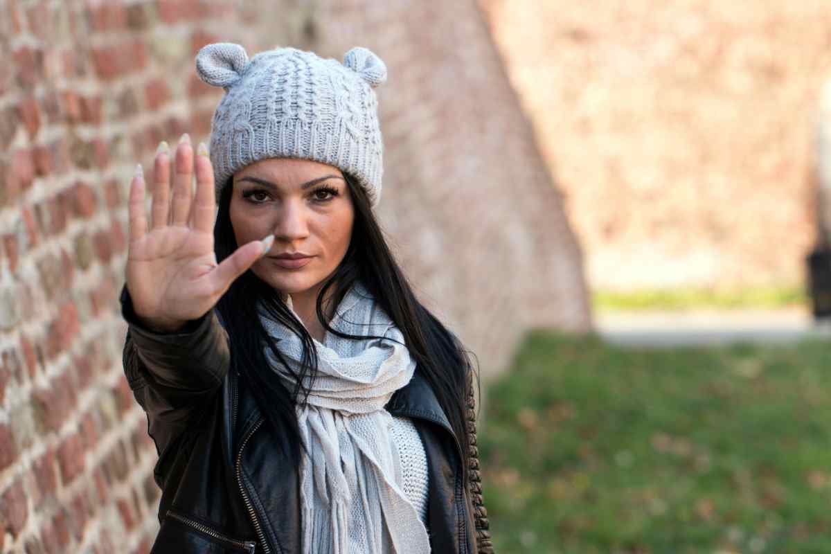 una donna con la mano alzata dice stop alla violenza