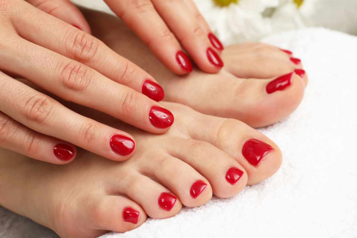 mani su piedi e unghie laccate di rosso