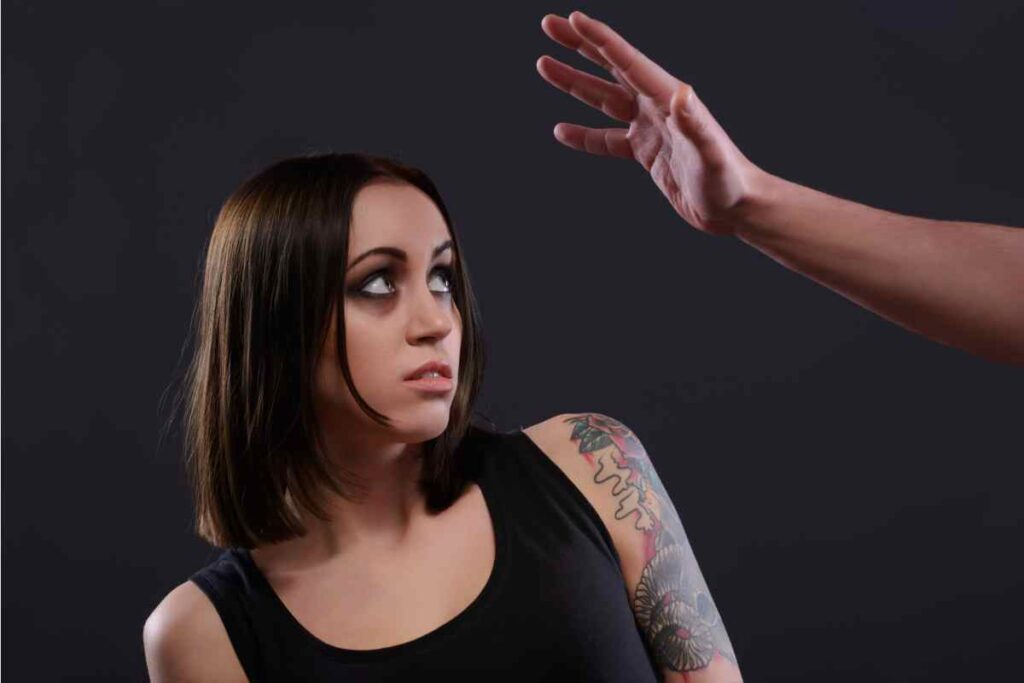 donna guarda con paura la mano di un uomo sopra la sua testa