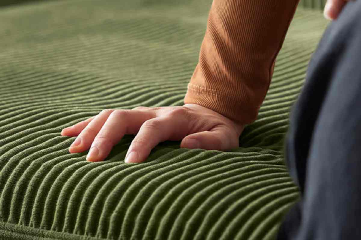 Mano poggiata su divano verde