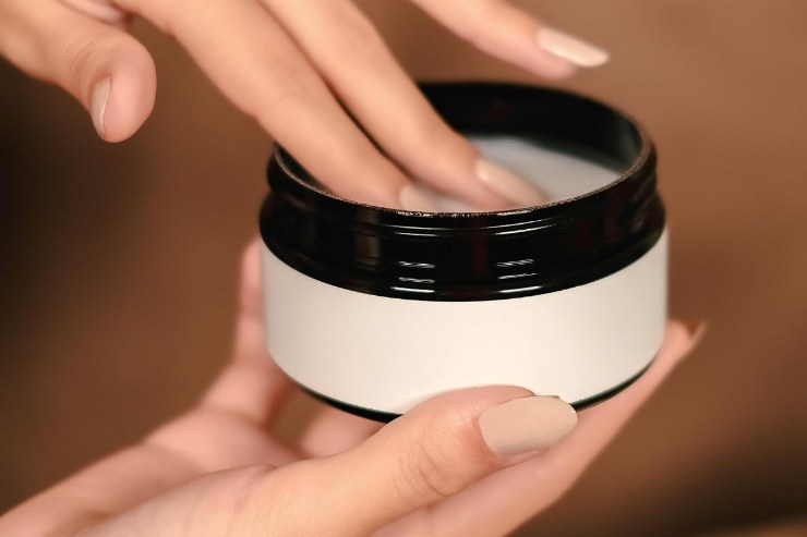 barattolo di crema in mano a una ragazza