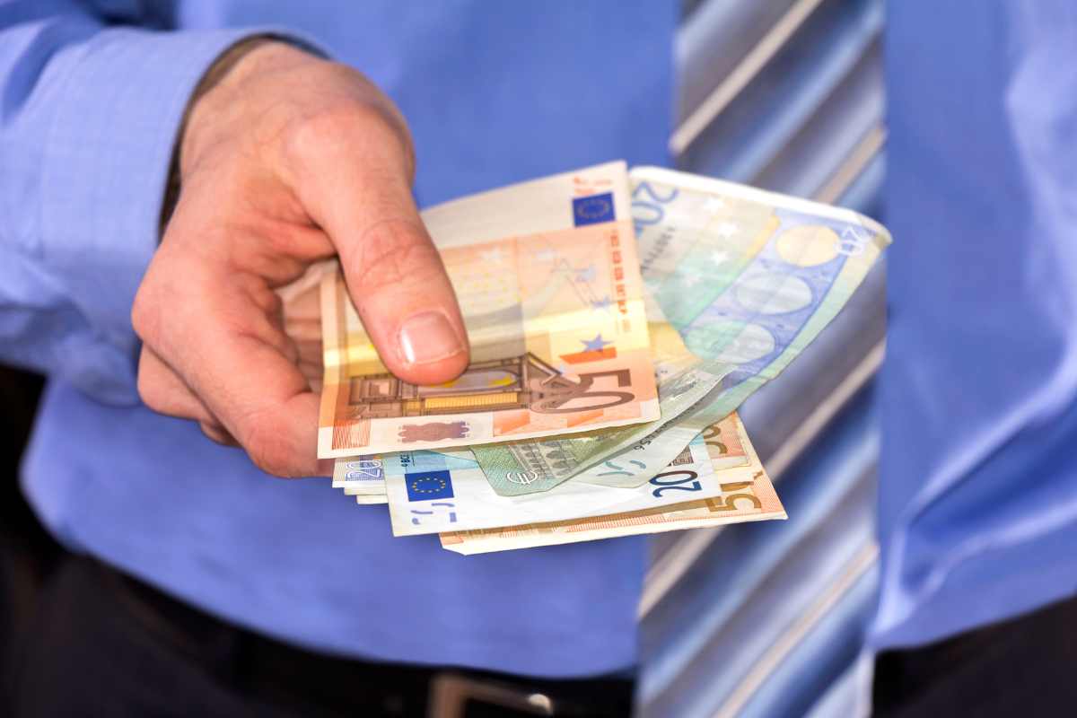 Un uomo che porge banconote in euro