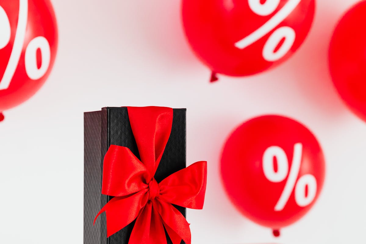 pacchetto nero con fiocco rosso contornato da palloncini rossi