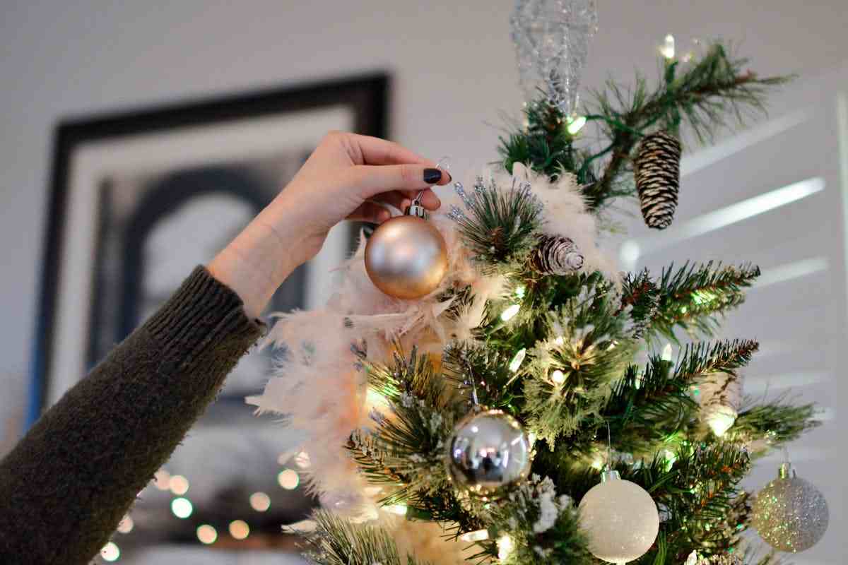 donna che mette pallina su albero di natale