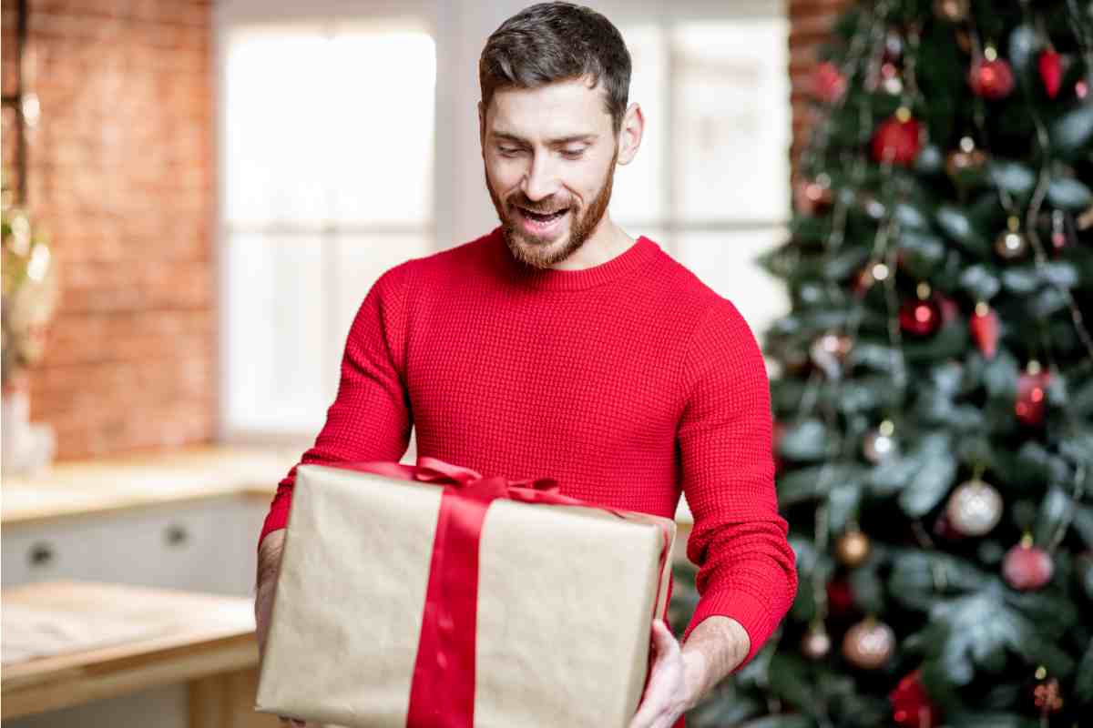 Un ragazzo tiene in mano una scatola di regali di Natale per lui