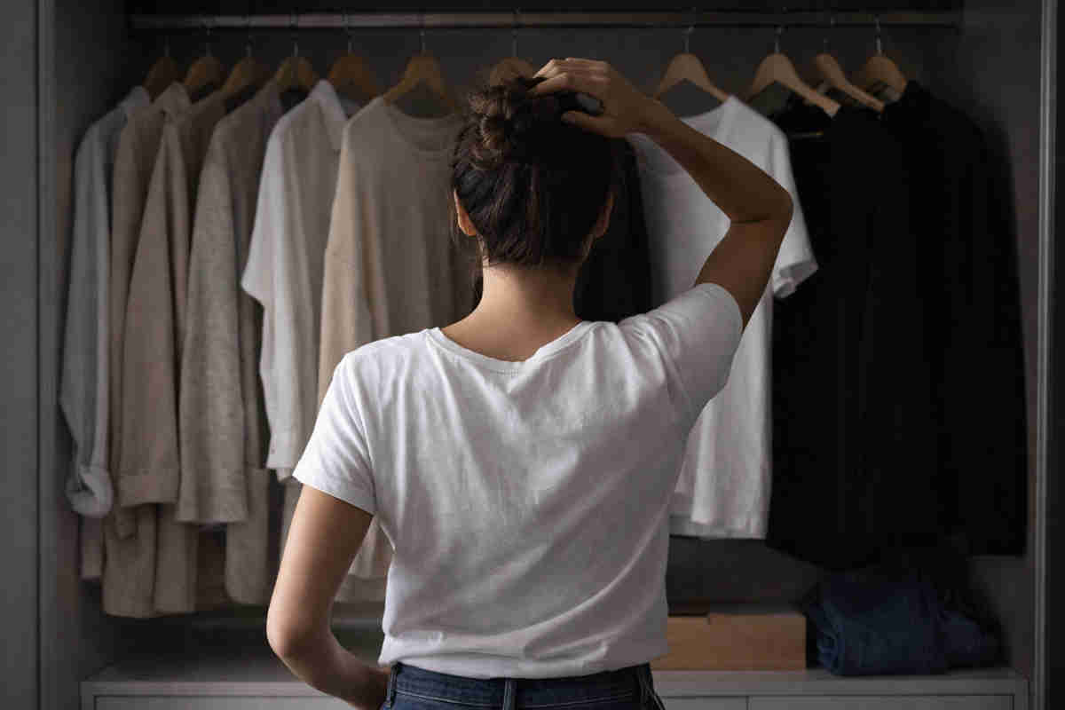 Ragazza davanti a degli abiti in armadio e non sa cosa indossare