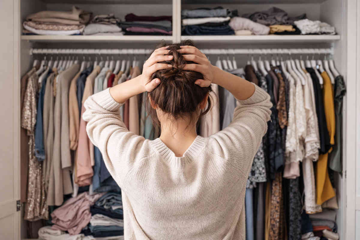 Donna davanti all'armadio aperto e non riesce a scegliere cosa indossare