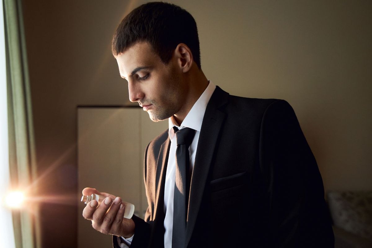 uomo che guarda flacone profumo