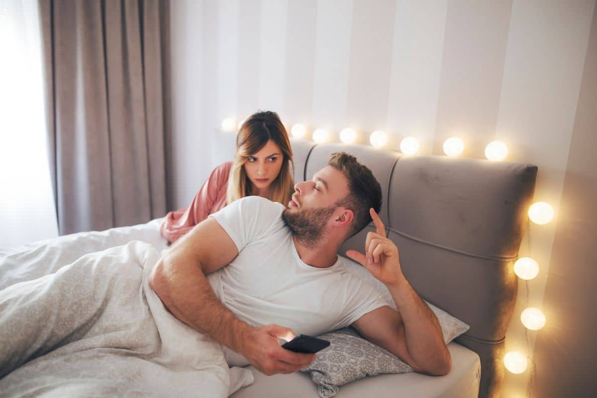 Coppia a letto, uomo con smartphone