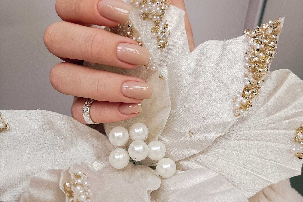 mano con unghie rosa che stringe fiore finto