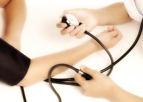Patient is being observed by doctor measuring blood pressure