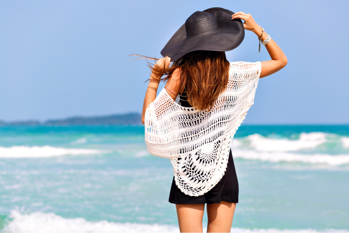 Ragazza al mare di spalle con un cappello di paglia