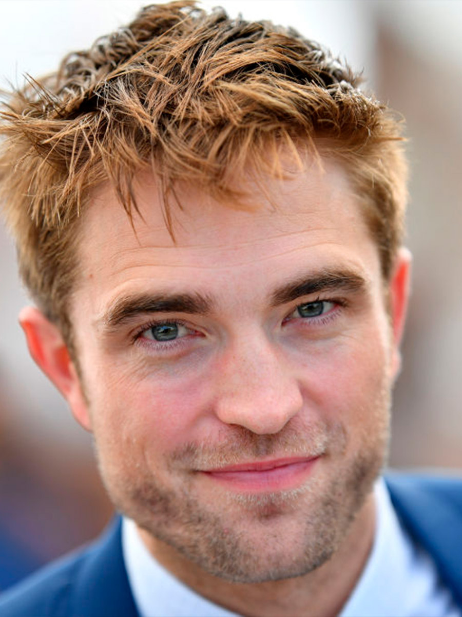 Robert Pattinson sorridente con una giacca blu