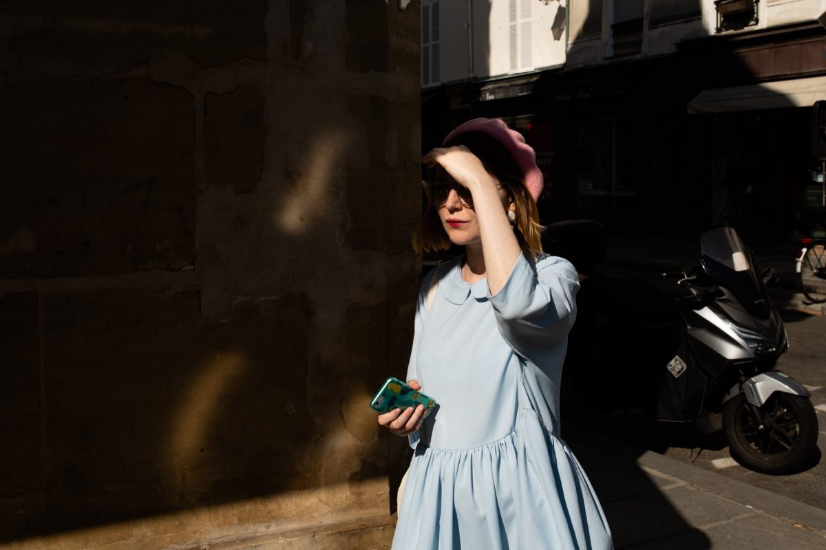Una ragazza French style con un vestito azzurro, il basco rosa e il rossetto rosso nella penombra