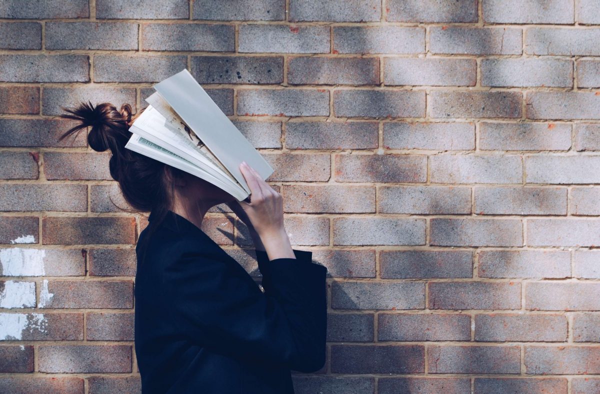 Una ragazza si copre il viso con un libro