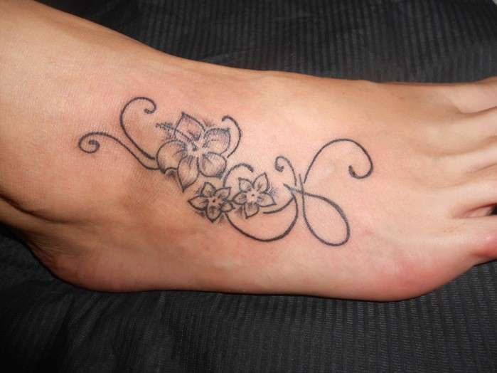 Tatuaggio sul piede con lettera e decorazione floreale