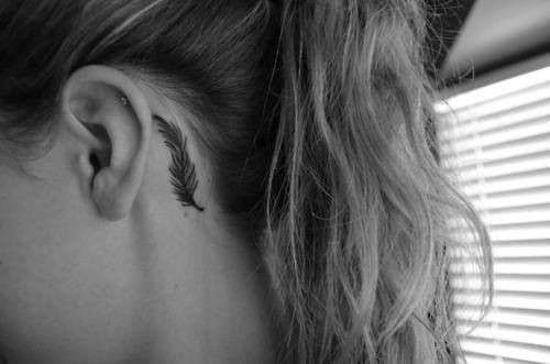 Piccolo tattoo con piccola piuma dietro l'orecchio
