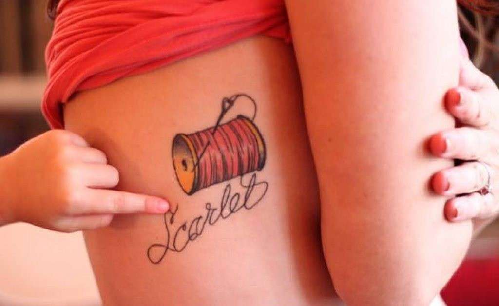 Tatuaggio con scritta, ago e filo