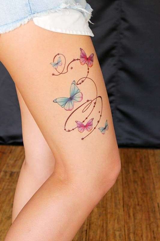Tatuaggio farfalle con stelline sulla coscia