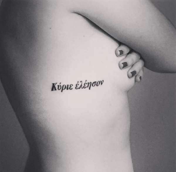 Tatuaggio frase in greco tra seno e fianco