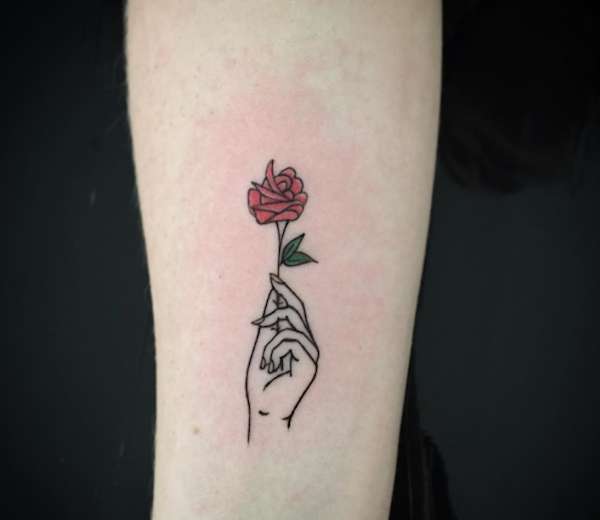 Tatuaggio con mano che regge una piccola rosa rossa