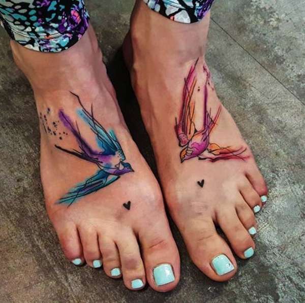 Tatuaggio con rondini colorate sui piedi