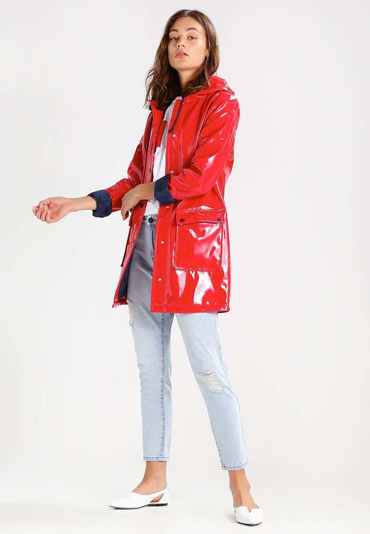 Trench in vinile rosso Topshop e jeans chiari