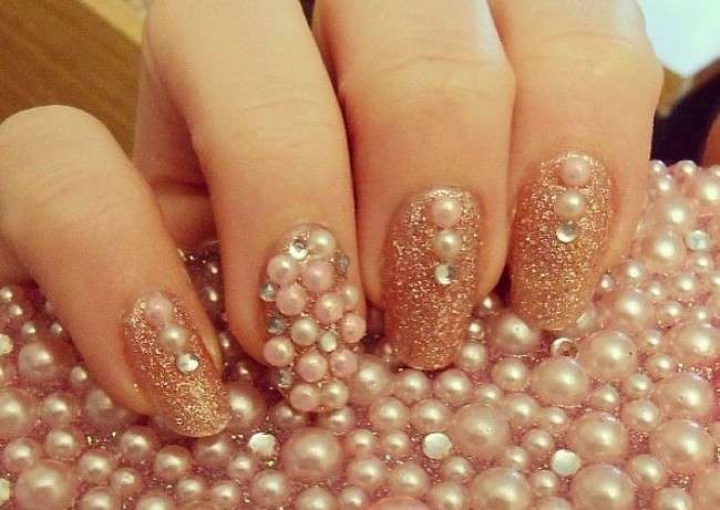 Unghie natalizie glitterate nei toni dell'oro con perle