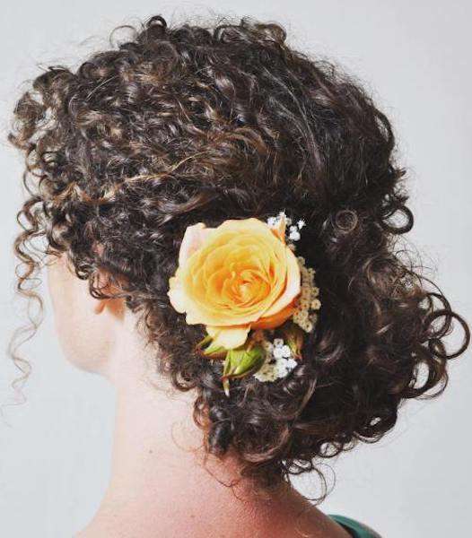 Capelli lunghi ricci raccolti con fiore