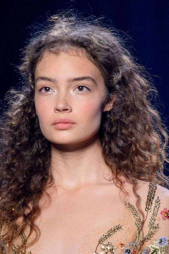 Capelli ricci semiraccolti in acconciatura con fermaglio