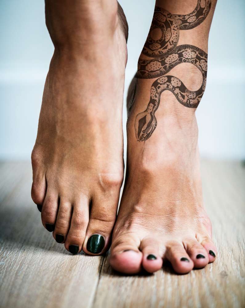 Tatuaggio femminile serpente sulla gamba